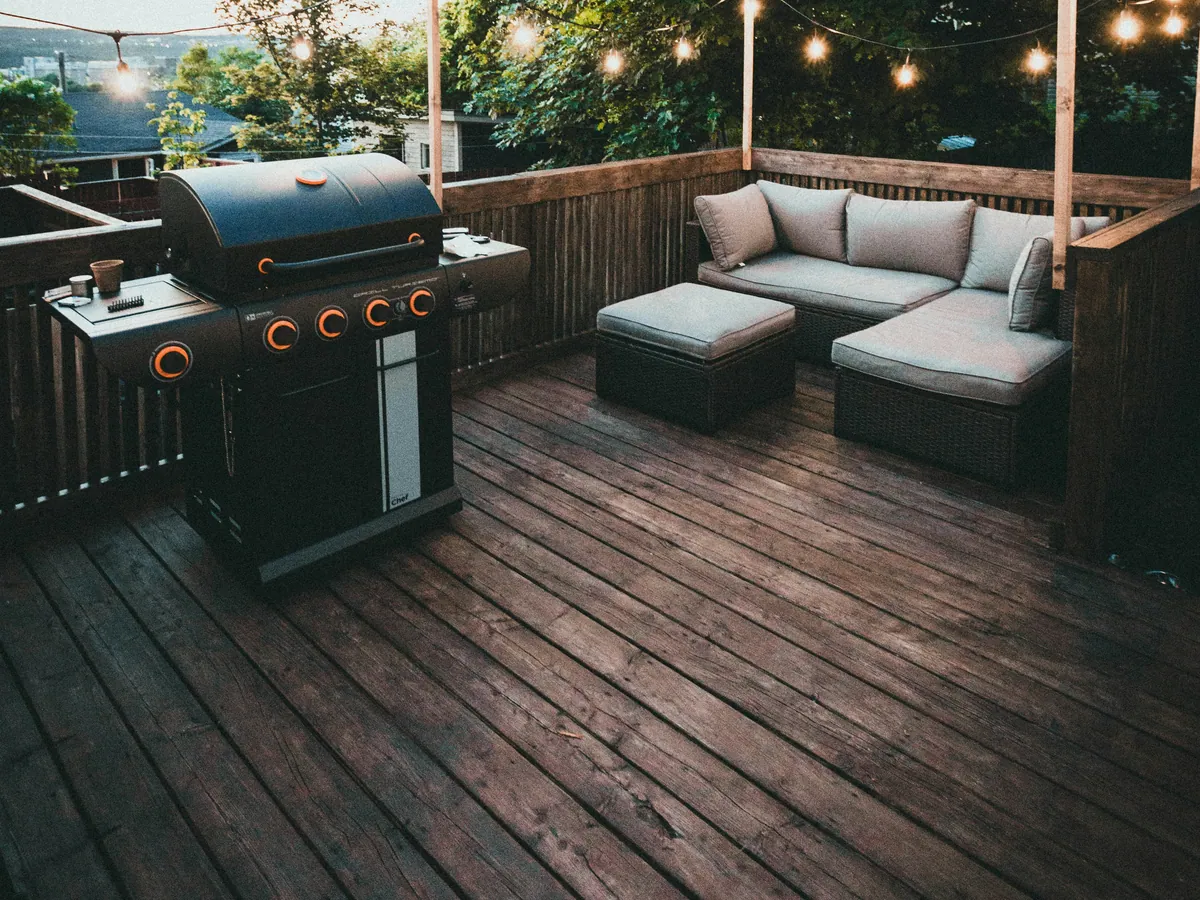 A finished backyard wood deck in Nashville with outdoor seating, a grill, and string lights at dusk