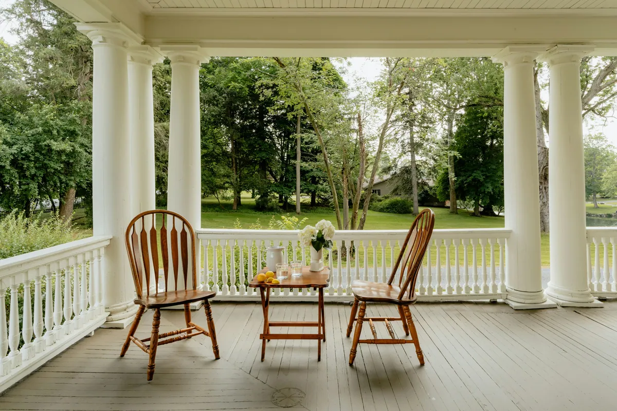A classic covered porch in Nashville with columns, seating, and a green backyard view